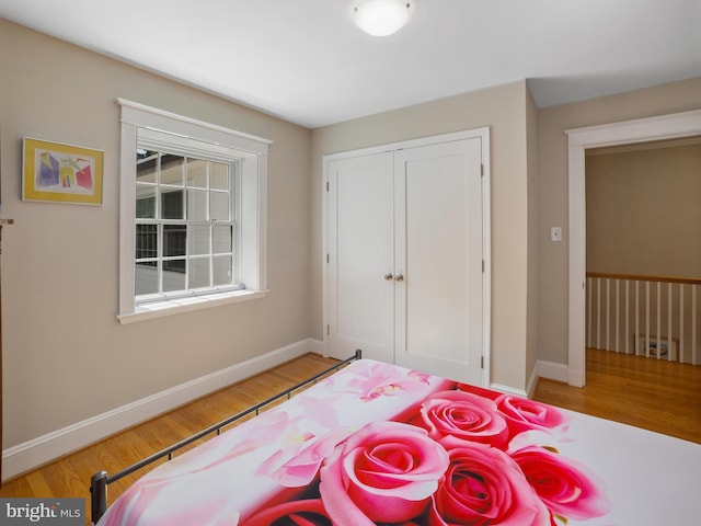 bedroom featuring light wood-style floors, baseboards, and a closet