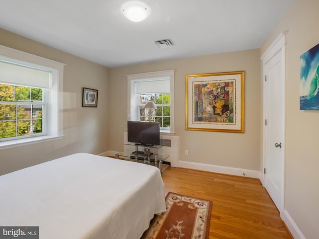 bedroom featuring baseboards, visible vents, multiple windows, and light wood-style floors