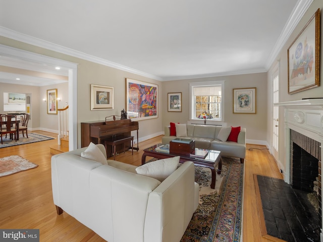 living room featuring baseboards, ornamental molding, light wood finished floors, and a fireplace