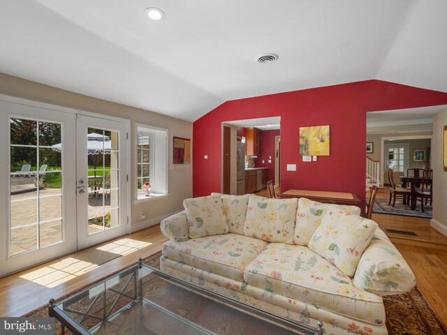living room with french doors, baseboards, wood finished floors, lofted ceiling, and visible vents