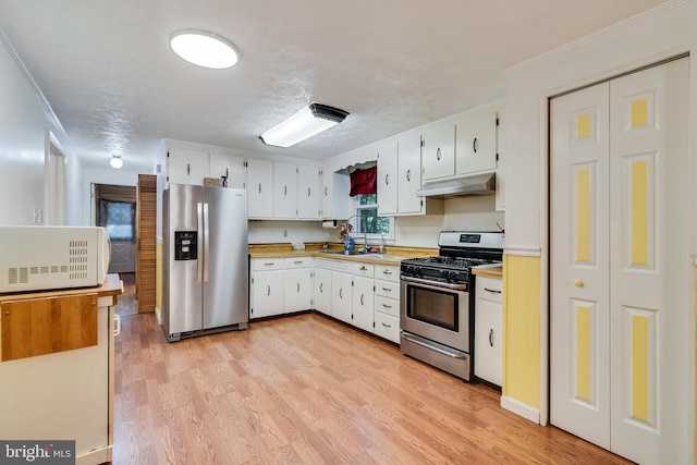 5605 Chapmans Landing Rd, Indian Head, MD 20640 - kitchen with appliances with stainless steel finishes, light countertops, under cabinet range hood, light wood-style floors, and white cabinets