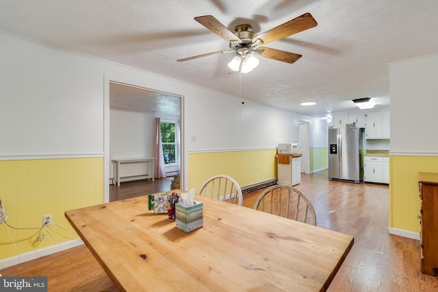 5605 Chapmans Landing Rd, Indian Head, MD 20640 - dining room with wainscoting, ceiling fan, light wood-type flooring, a textured ceiling, and a baseboard radiator