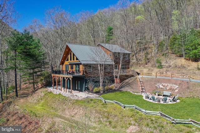 back of property featuring a patio, stairway, a deck, a lawn, and metal roof