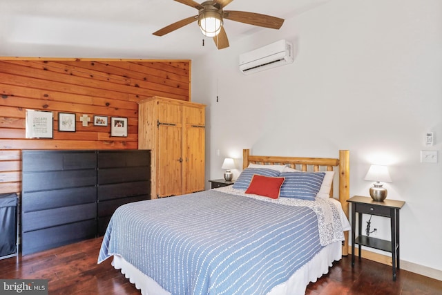 bedroom with a wall mounted air conditioner, wooden walls, ceiling fan, and wood finished floors