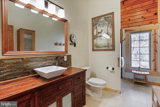 bathroom featuring tasteful backsplash, tile patterned floors, baseboards, and toilet