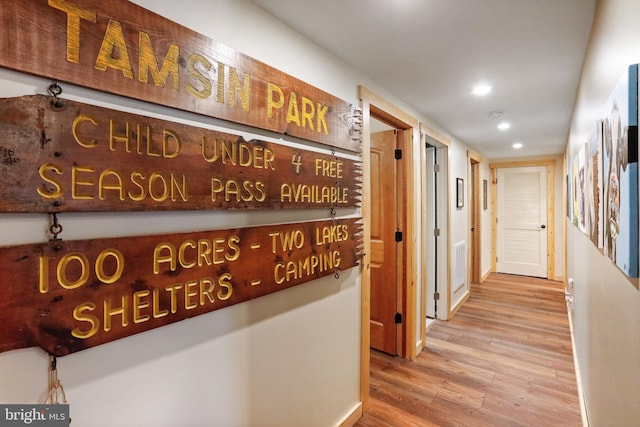 corridor featuring wood finished floors, baseboards, and recessed lighting