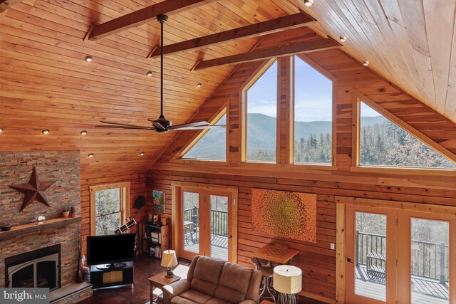 living area featuring plenty of natural light, french doors, a stone fireplace, and wooden ceiling
