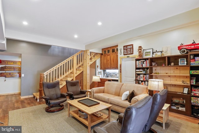 living room with baseboards, light wood finished floors, recessed lighting, and stairs