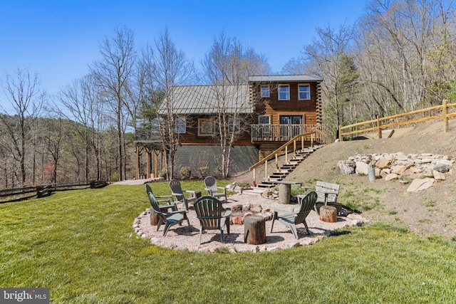 rear view of house with a yard, an outdoor fire pit, fence, stairway, and a wooden deck