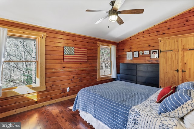 bedroom with wood walls, ceiling fan, hardwood / wood-style flooring, and lofted ceiling
