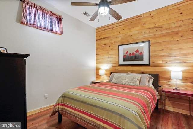 bedroom featuring wood walls, wood-type flooring, and visible vents