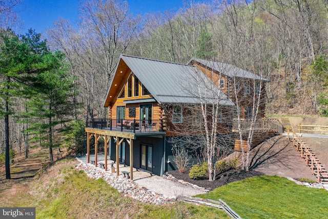 exterior space with metal roof, a deck, a front lawn, and log exterior