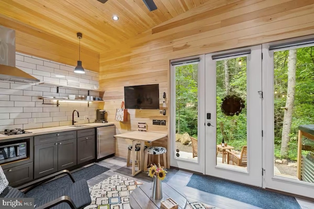 doorway featuring wooden ceiling, indoor wet bar, a sink, and wooden walls
