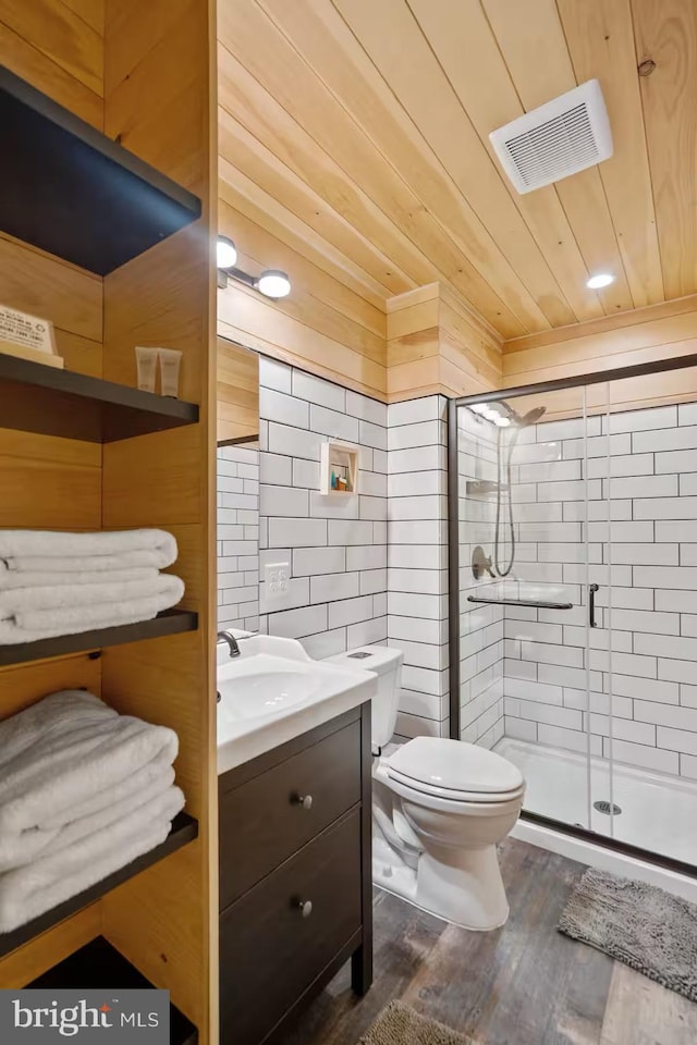 bathroom featuring vanity, a stall shower, toilet, visible vents, and tile walls