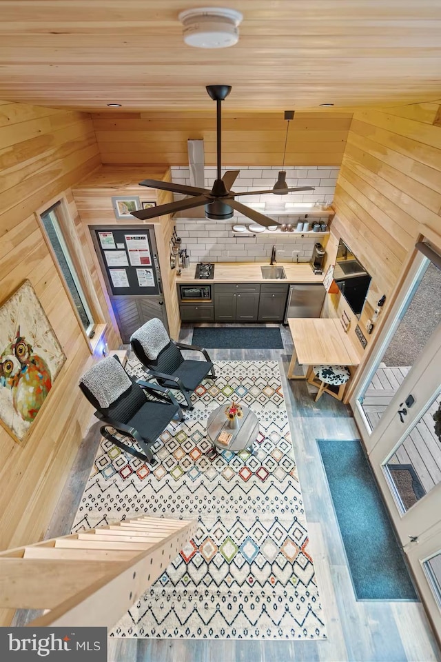 interior space featuring wooden ceiling, wooden walls, a ceiling fan, and wood finished floors