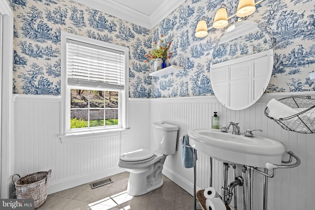 half bathroom with ornamental molding, visible vents, toilet, and wainscoting