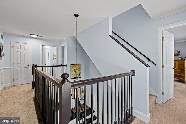 corridor with an upstairs landing, baseboards, ornamental molding, and carpet floors