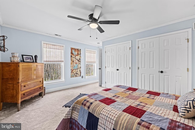 bedroom with visible vents, baseboards, ornamental molding, multiple closets, and carpet flooring