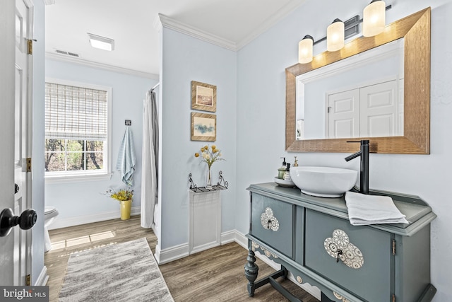 interior space featuring visible vents, baseboards, ornamental molding, and wood finished floors