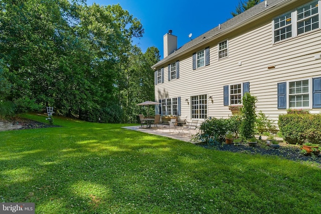 rear view of house featuring a patio, a chimney, and a lawn