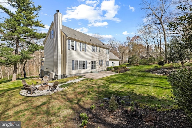 back of property with a patio, a yard, a chimney, and an outdoor fire pit