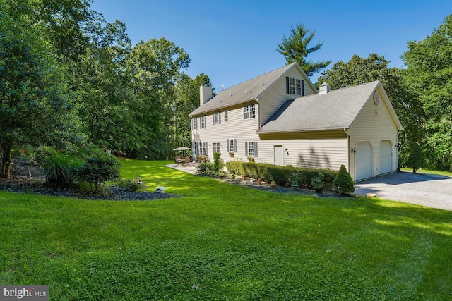 exterior space with a yard, an attached garage, and a chimney