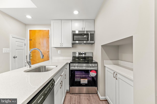 1516 Lancaster St, Baltimore, MD 21231 - kitchen featuring appliances with stainless steel finishes, white cabinets, light wood finished floors, light stone countertops, and recessed lighting