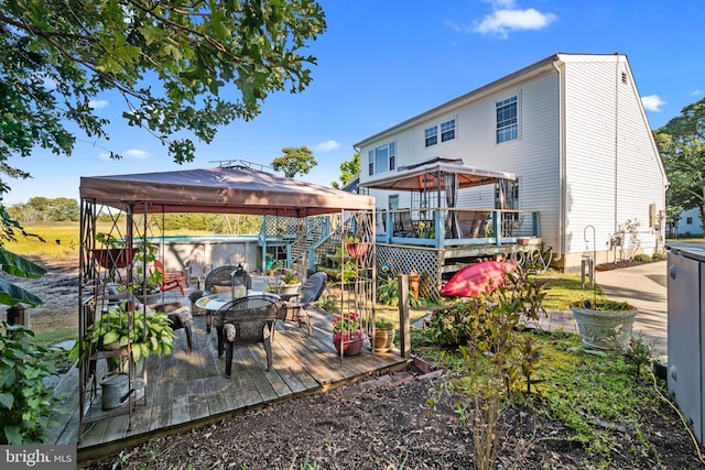 back of house featuring a wooden deck, a gazebo, a jacuzzi, and stairway