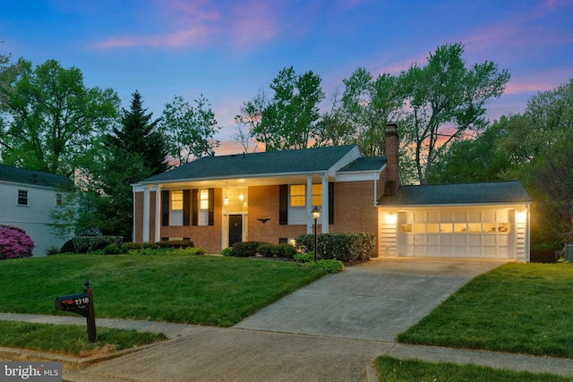 view of front of house with a chimney, brick siding, a garage, concrete driveway, and a lawn