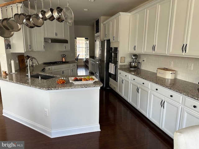 8537 Pine Springs Dr, Severn, MD 21144 - kitchen featuring under cabinet range hood, white cabinetry, a sink, stone countertops, and freestanding refrigerator