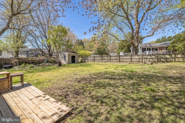 view of yard featuring a fenced backyard, a wooden deck, a shed, and an outdoor structure