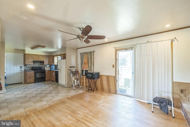 kitchen featuring a ceiling fan, brown cabinetry, black electric range, white fridge with ice dispenser, and wood walls