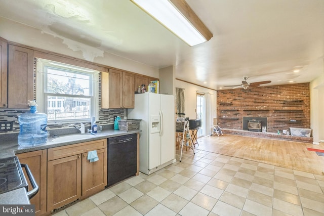kitchen featuring black dishwasher, a wealth of natural light, white refrigerator with ice dispenser, and a sink