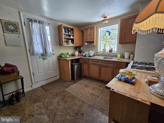 kitchen with light countertops, a sink, exhaust hood, and brown cabinets