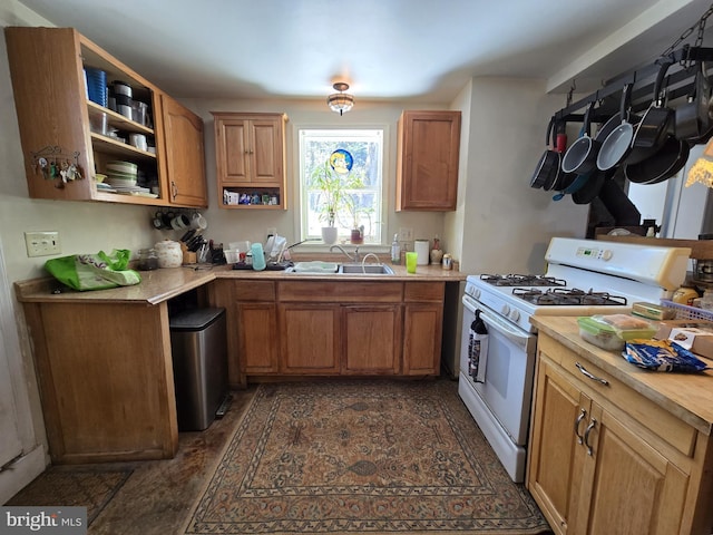 kitchen with light countertops, white range with gas stovetop, a sink, and brown cabinetry
