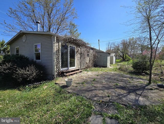 back of house with an outdoor structure and a patio area