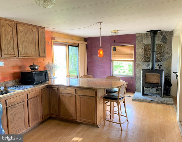 kitchen featuring a peninsula, black microwave, light wood finished floors, and a wealth of natural light