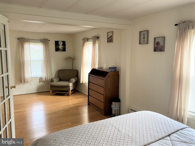 bedroom featuring multiple windows, baseboard heating, and wood finished floors