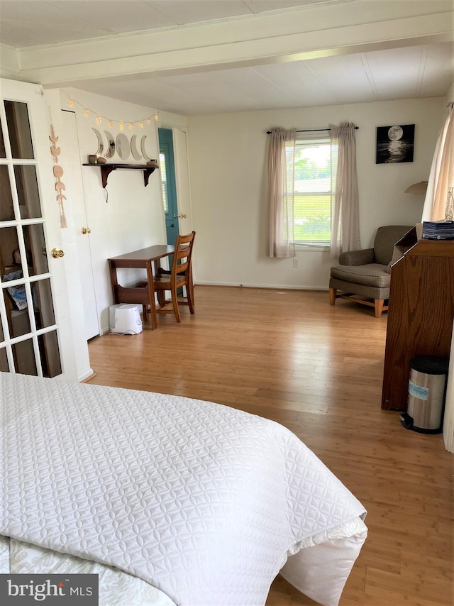 bedroom with beamed ceiling and wood finished floors