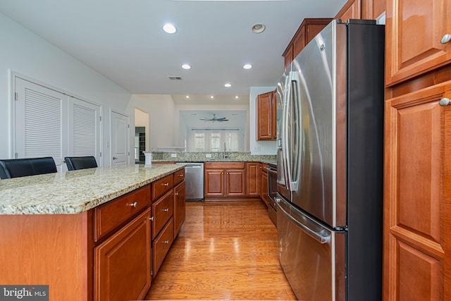 19062 Timbercreek Dr Unit 46, Milton, DE 19968 - kitchen with recessed lighting, stainless steel appliances, light wood-style floors, light stone countertops, and brown cabinetry