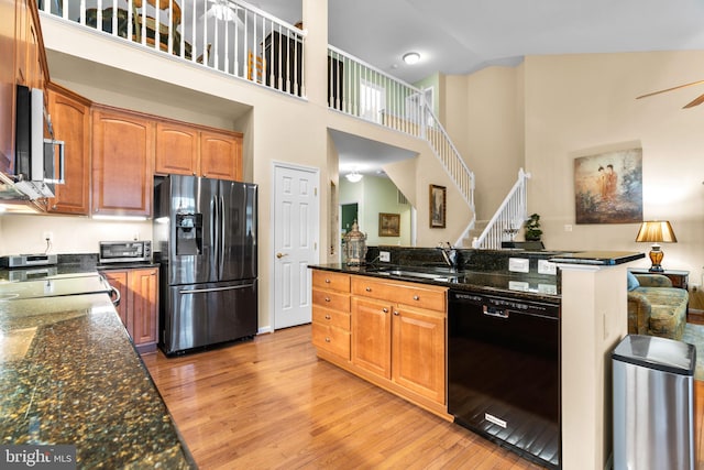 kitchen featuring a sink, ceiling fan, stainless steel appliances, light wood-style flooring, and high vaulted ceiling