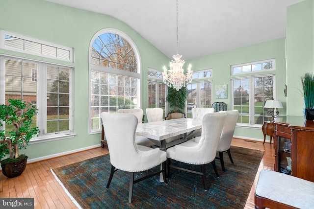 dining room featuring baseboards, high vaulted ceiling, hardwood / wood-style flooring, and an inviting chandelier