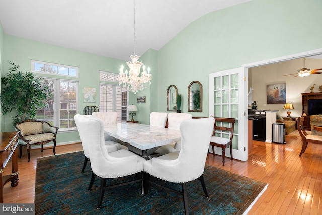 dining area with high vaulted ceiling, ceiling fan with notable chandelier, and hardwood / wood-style floors