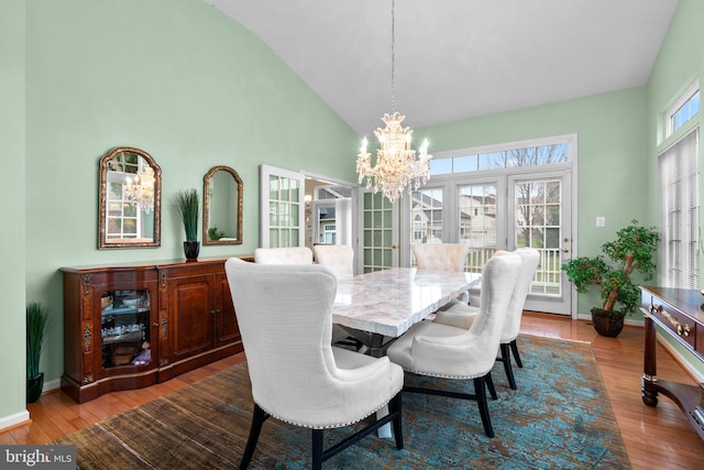 dining area with high vaulted ceiling, a notable chandelier, baseboards, and dark wood finished floors