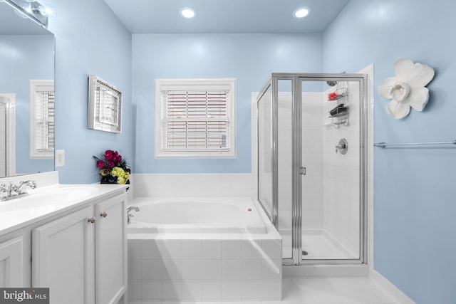 bathroom featuring a stall shower, a garden tub, and vanity