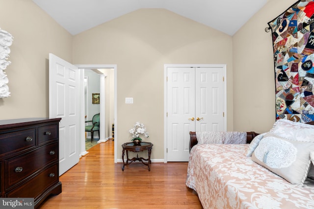 bedroom featuring a closet, light wood-type flooring, baseboards, and lofted ceiling