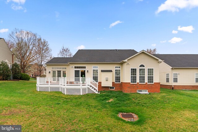 back of property featuring a wooden deck and a lawn