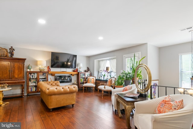 living area featuring dark wood-style floors, a glass covered fireplace, visible vents, and recessed lighting