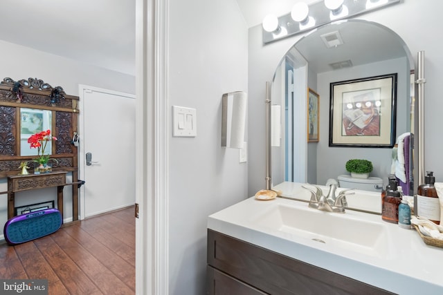 bathroom featuring toilet, vanity, wood finished floors, and visible vents
