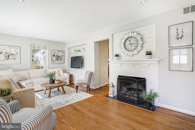living area featuring baseboards, recessed lighting, a fireplace, visible vents, and wood finished floors